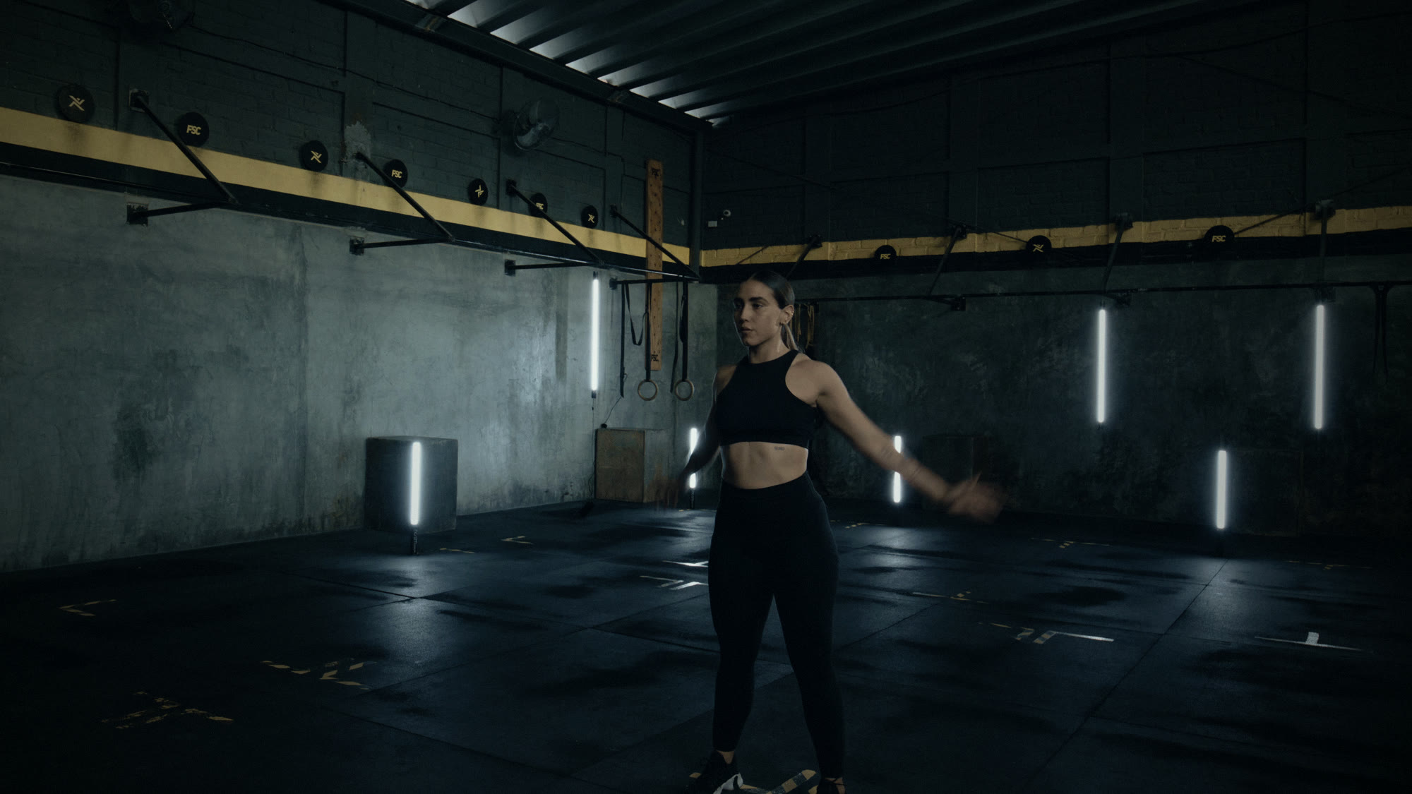 A lifter warming up with slow arm circles on the gym floor