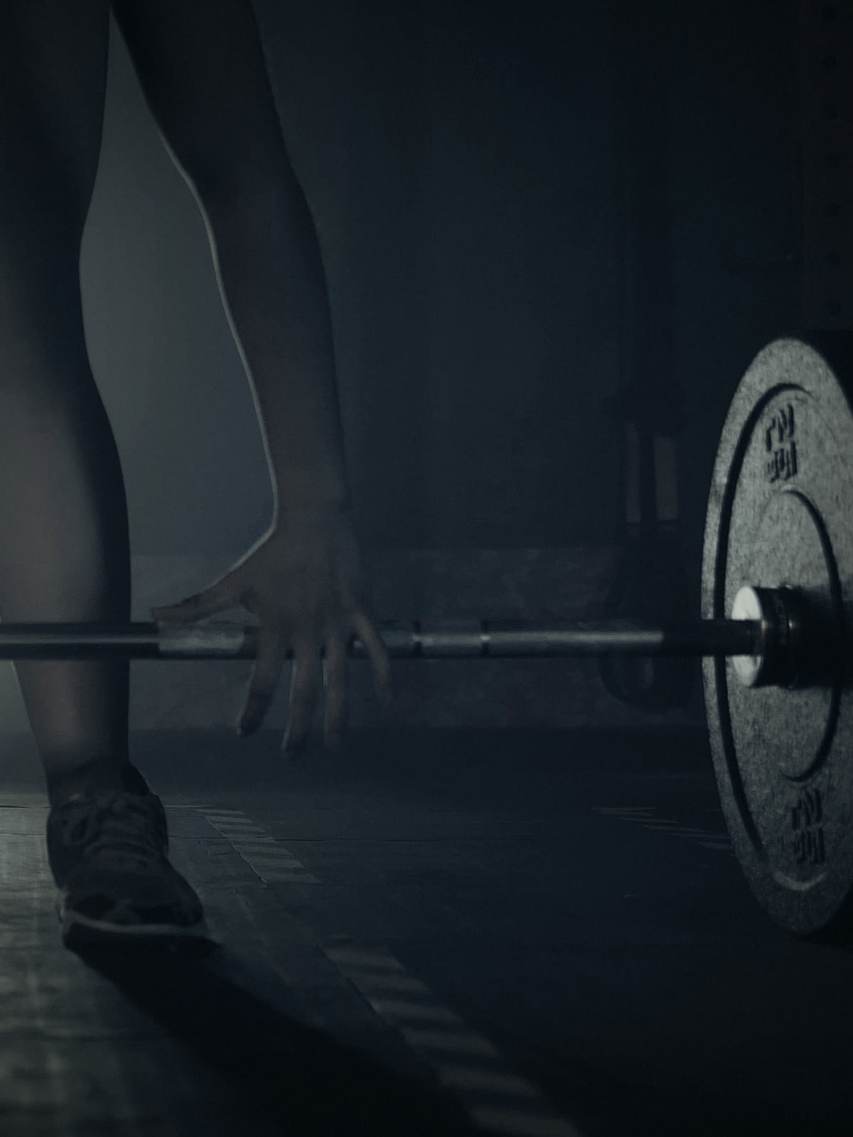 The head coach's hand set on a loaded barbell