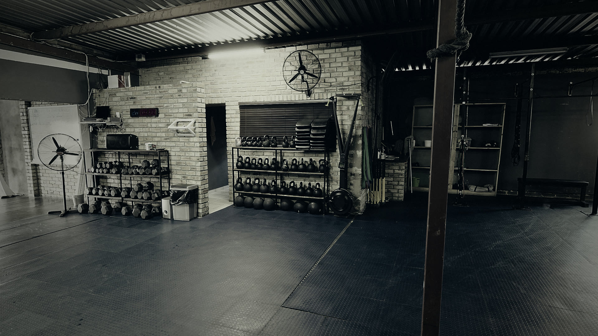 The training floor: kettlebell and dumbbell racks, rubber matting and the rig